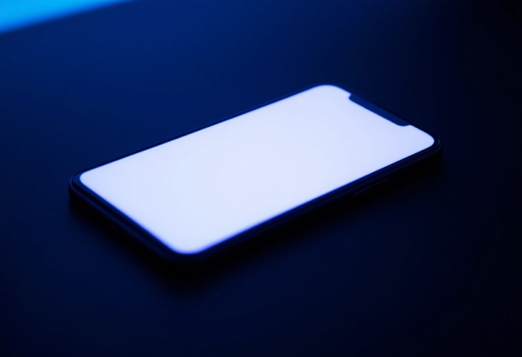 Smartphone pose face visible sur une surface sombre, lumiere bleue